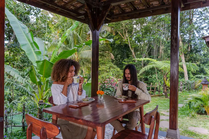 Two guests sharing a meal at a wooden table in the Pendopo